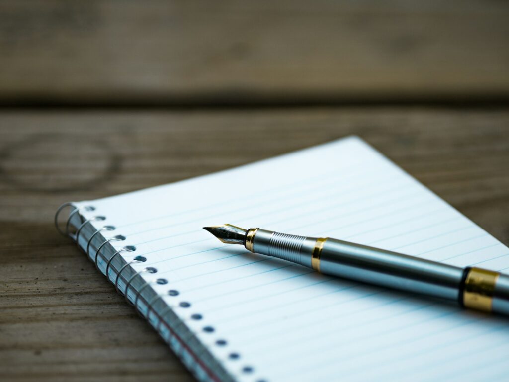 A fountain pen resting beside an open notebook